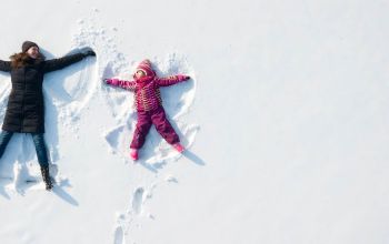 Adult and child making snow angels